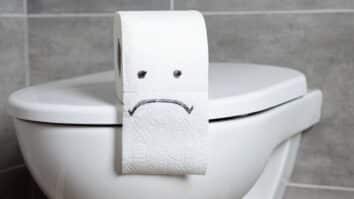Papel-higiênico com expressão de tristeza desenhada com caneta sobre vaso sanitário