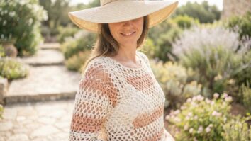 Mulher sorridente usando blusa de croche artesanal em tons neutros em ambiente externo de verao com luz natural