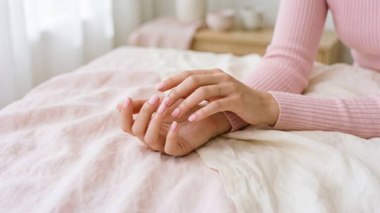 Mãos femininas com unha pintada rosa bebê