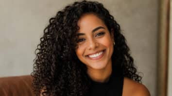 Mulher com cabelo cacheado sorrindo