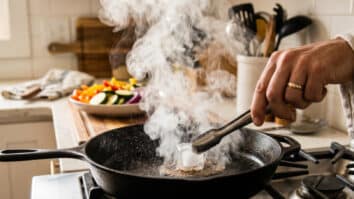 Pessoa passando cubo de gelo em frigideira quente