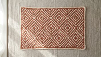 Peca de croche mosaico com padroes geometricos perfeitos em duas cores contrastantes sobre fundo neutro