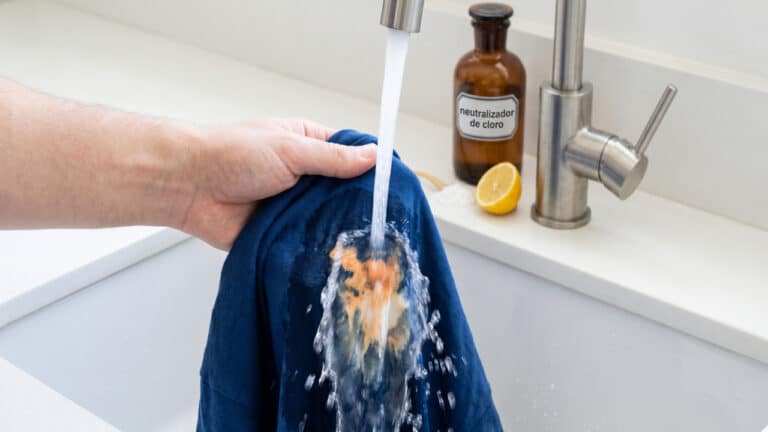 Água corrente da torneira sobre mancha de água sanitária em camisa azul escura