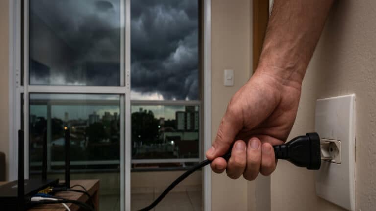 Desconectando tomada do roteador com o tempo fechando para tempestade
