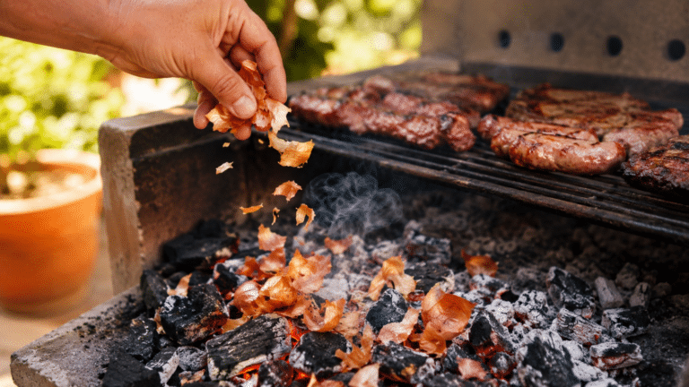 Cascas de cebola sendo jogadas nas brasas da churrasqueira para aromatizar o churrasco de forma simples e caseira.