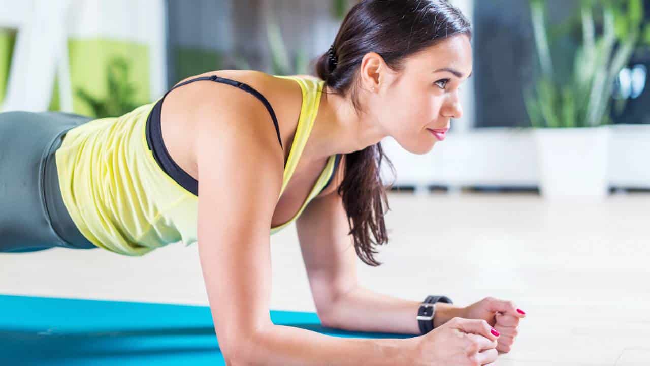 Mulher fazendo prancha abdominal em tapete